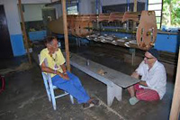 Two men, one in a chair and one on the floor, sit and talk in a room